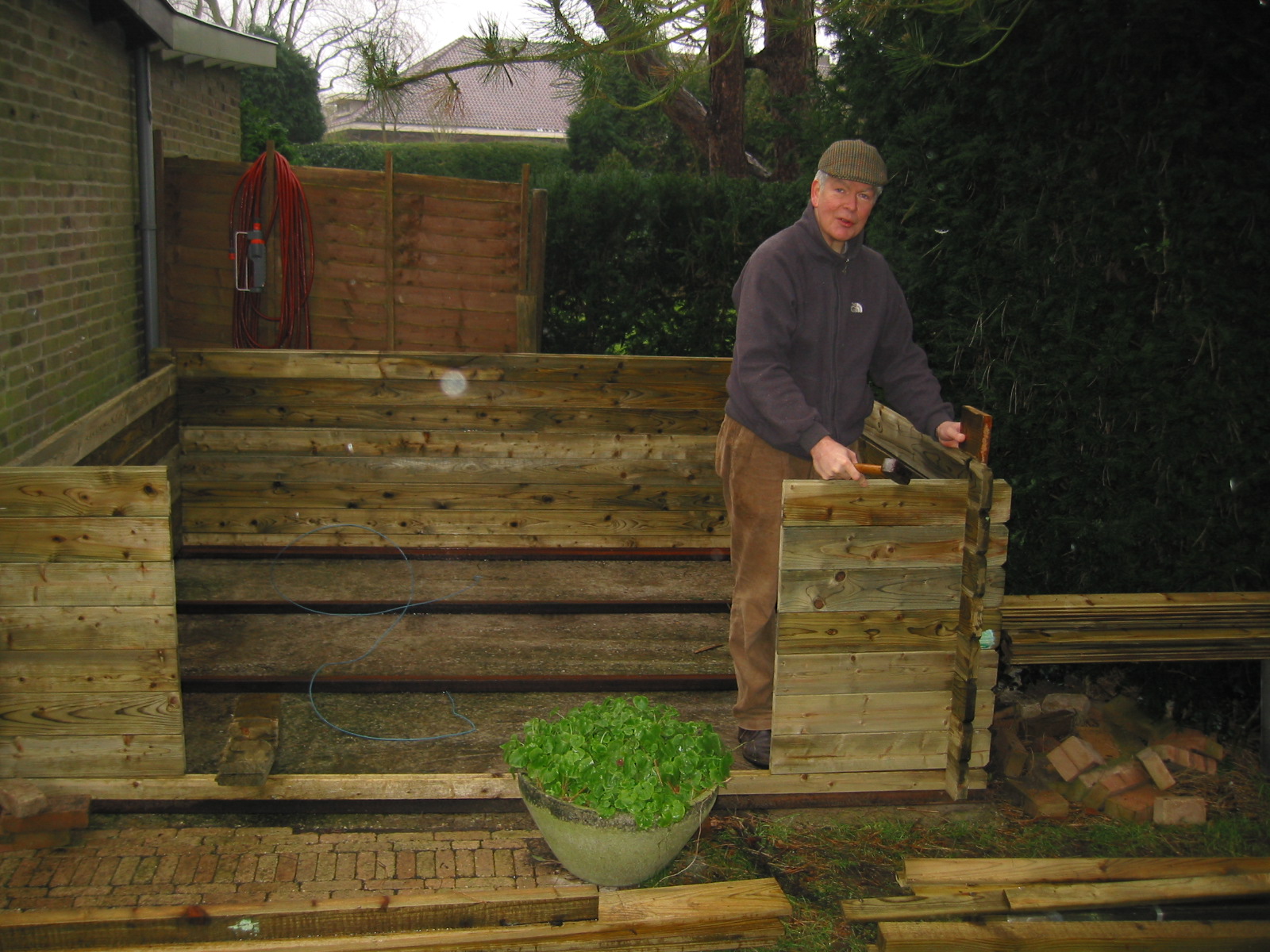 Hans bouwt een houten schuurtje in de tuin.